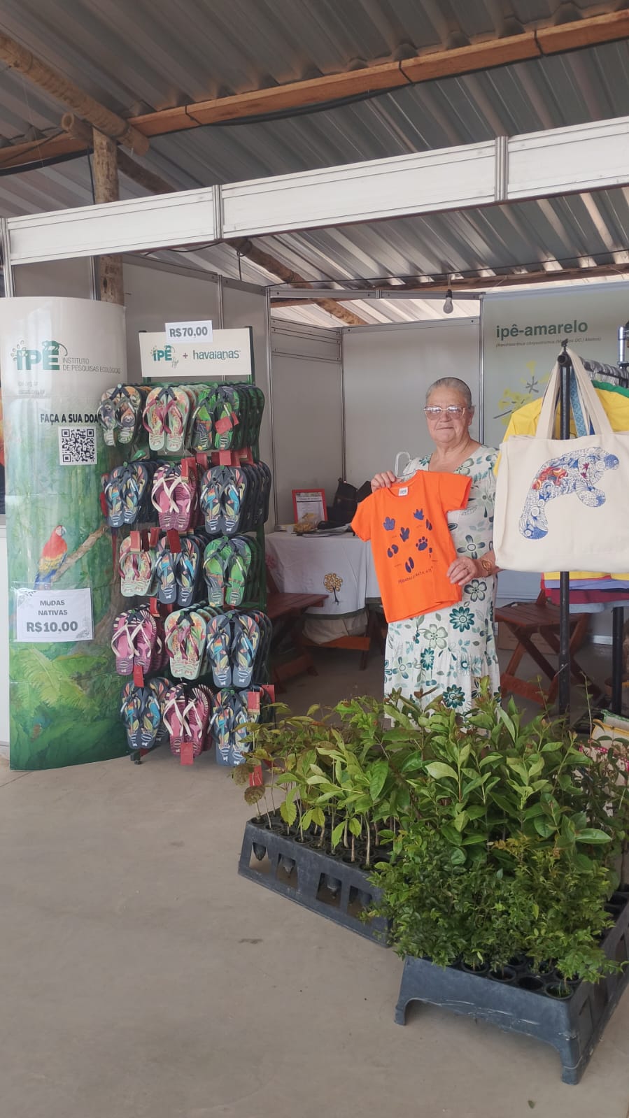 Bordadeira do projeto Costurando o Futuro mostra camiseta pegadas da linha infantil
