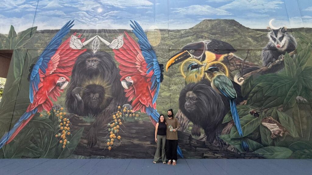 A pesquisadora Gabriela Rezende e o muralista Fernando Berg na inauguração ao mural que homenageia o mico-leão-preto e a biodiversidade da região, em Teodoro Sampaio. 